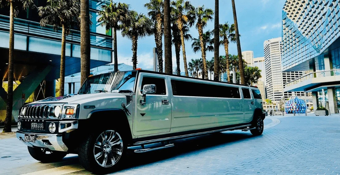 White GMC Hummer H2 Super Stretch limo on downtown SF street lined with palm trees