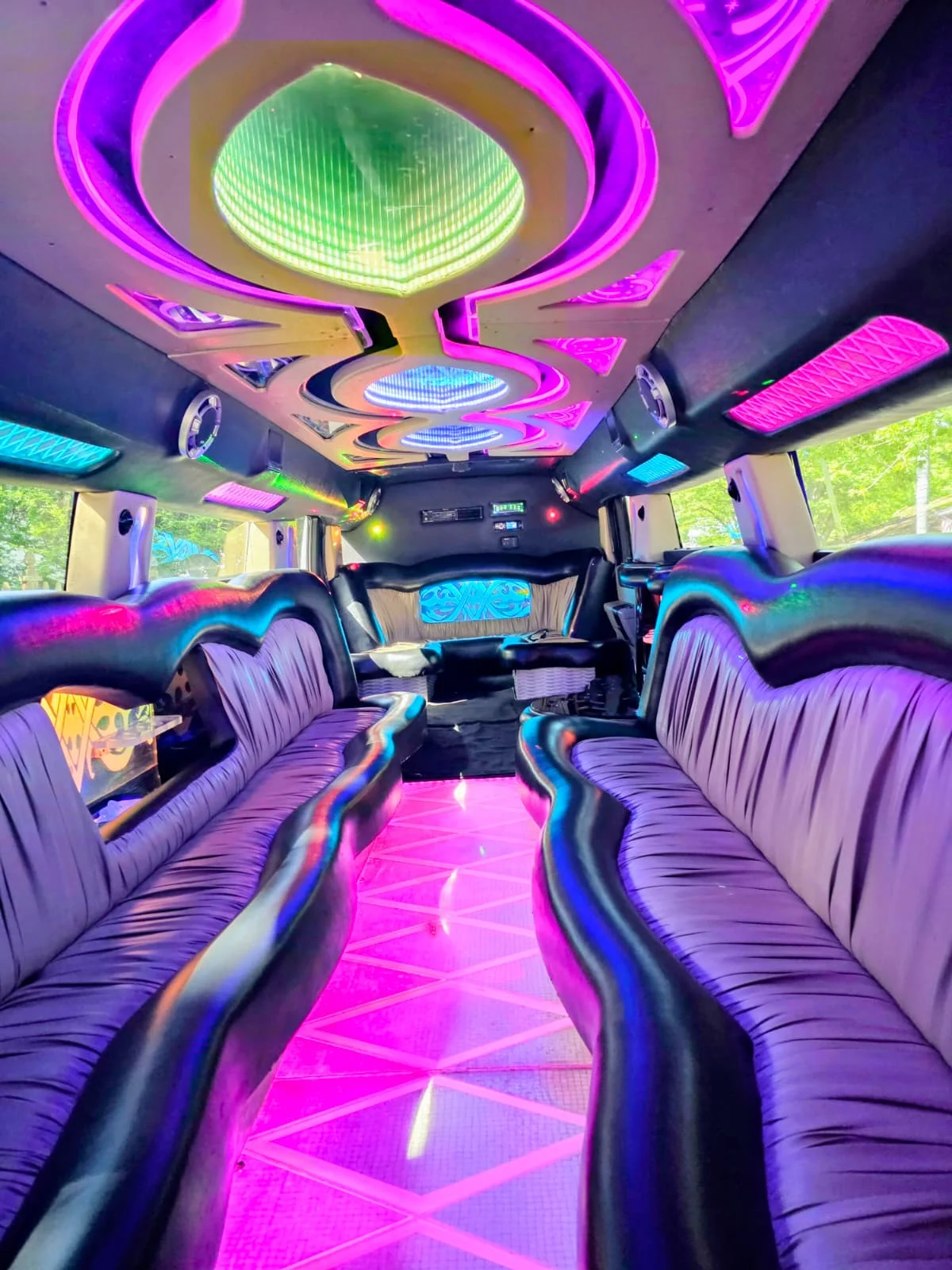 Hummer stretch limo interior with pink and magenta LED mood lighting, purple checkered floor, disco ceiling